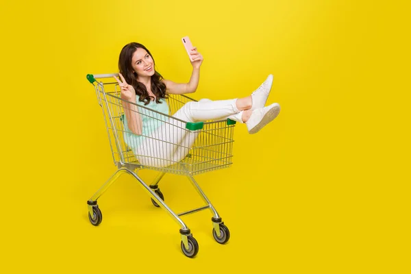 Portrait pleine longueur de dame gaie drôle assis trolley faire selfie show v-signe isolé sur fond de couleur jaune — Photo