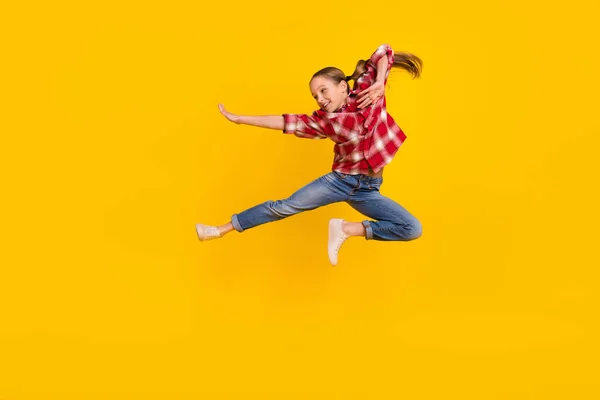 Foto de colegial brillante fresco vestido camisa a cuadros saltando alto practicar karate aislado color amarillo fondo —  Fotos de Stock