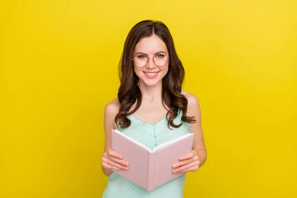 Foto de adorable encantadora joven hembra haciendo tarea lectura libro novela aislada sobre fondo de color amarillo —  Fotos de Stock