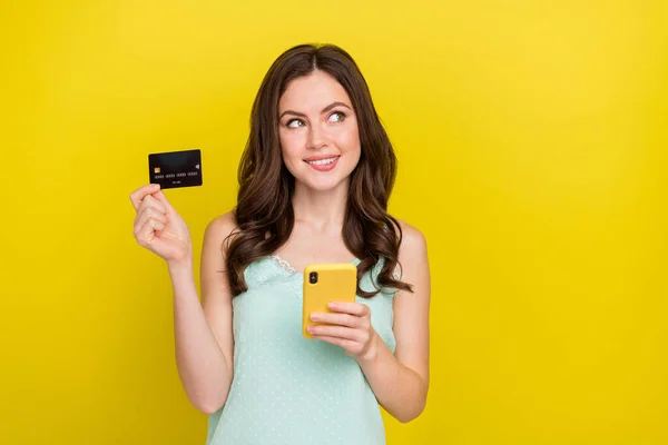 Zdjęcie adorable dobry nastrój marzycielski kobieta myśli o transakcji online nfc izolowane na żółtym tle koloru — Zdjęcie stockowe