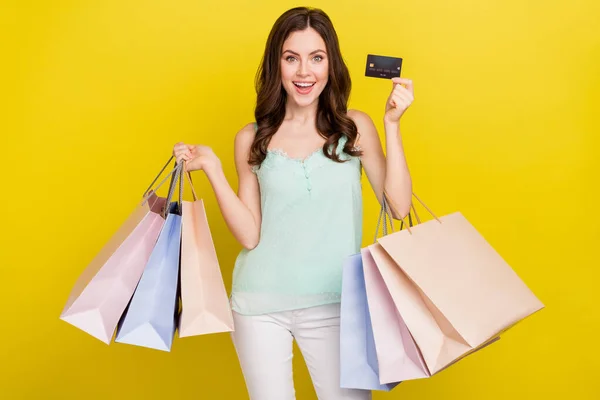 Foto de bonito bom humor feminino comprar roupas on-line usando seu cartão de crédito transação sem fio isolado em fundo de cor amarela — Fotografia de Stock