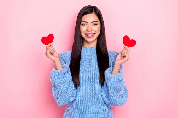 Retrato de menina alegre atraente segurando nas mãos dois pequenos cartões cardíacos isolados sobre fundo cor pastel rosa — Fotografia de Stock