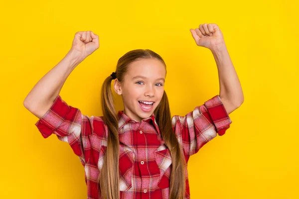 Foto anak sekolah yang beruntung manis mengenakan kemeja kotak-kotak tersenyum mengepalkan tinju terisolasi latar belakang warna kuning — Stok Foto