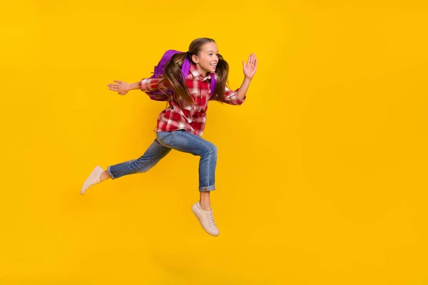 Foto de colegiala linda funky usar camisa a cuadros corriendo rápido saltar alto aislado color amarillo fondo —  Fotos de Stock