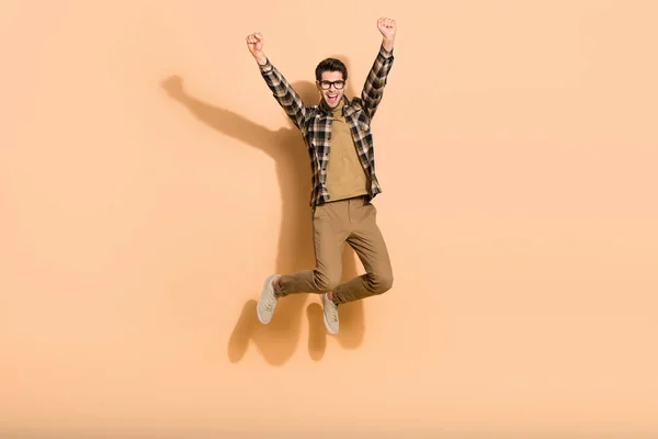 Full längd foto av glad bekymmerslös kille hoppa hög mästare knytnäve upp isolerad över pastell färg bakgrund — Stockfoto