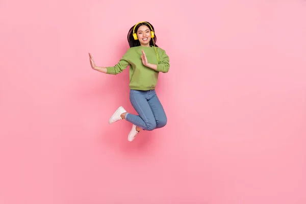 Full size photo of funky young lady jump listen music wear pullover jeans shoes isolated on pink background — ストック写真