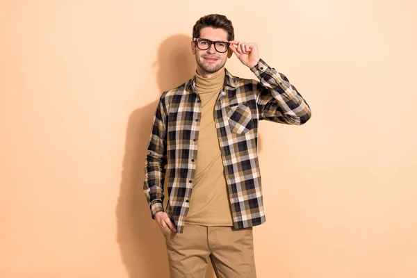 Portrait of attractive content skilled intellectual guy touching specs isolated over beige pastel color background — ストック写真