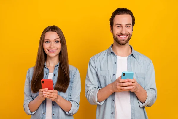 Photo de mignon jeune couple de cheveux bruns avec téléphone porter jeans chemise isolée sur fond jaune — Photo