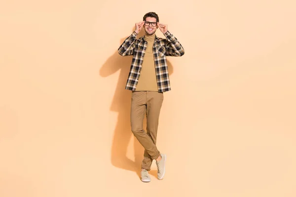 Full längd kroppsstorlek bild av attraktiv glad kille poserar rörande specifikationer isolerade över beige pastell färg bakgrund — Stockfoto