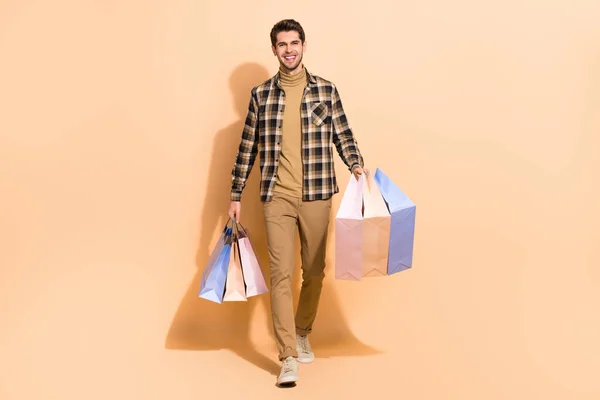 Full längd kroppsstorlek bild av attraktiv glad kille bär väskor nya saker isolerade över beige pastell färg bakgrund — Stockfoto