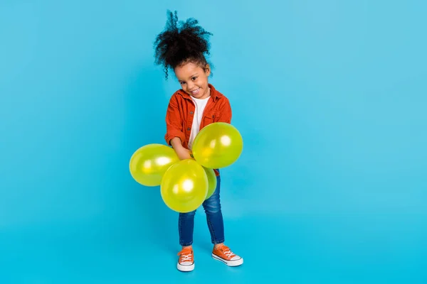 Фотографія солодкої хвилястої маленької дівчинки з повітряними кулями взуття джинсів сорочки ізольовано на синьому фоні — стокове фото