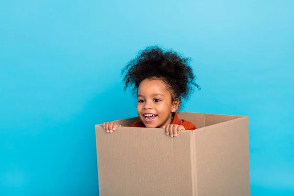 Photo of impressed curly little girl in box isolated on blue color background — ストック写真