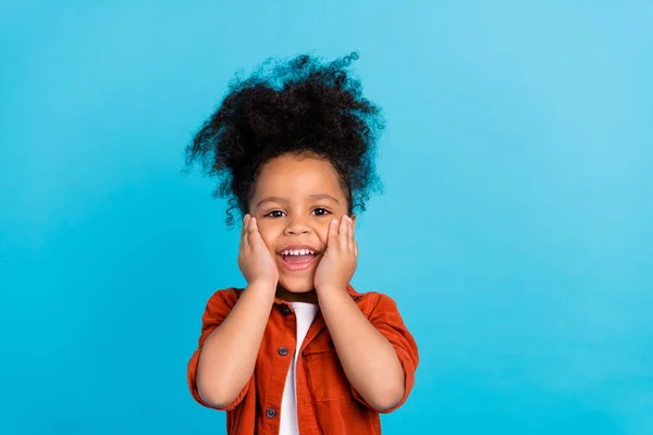 Портрет милой маленькой девочки с шевелюрой прическа услышать хорошие неожиданные новости касания щеки изолированы на синем фоне цвета — стоковое фото