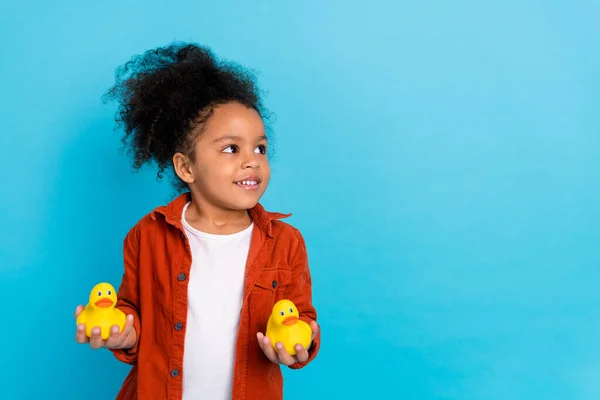 Фото гарної хвилястої маленької дівчинки, яка тримає іграшку, виглядає порожньою футболкою простору ізольованою на синьому кольорі — стокове фото