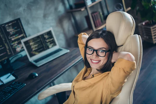 Porträtt av attraktiv glad flicka nörd hacker sitter vilande i stol cybersäkerhet genomförande på arbetsplatsen arbetsstation inomhus — Stockfoto