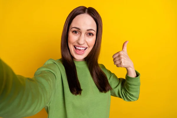 Self-portrait of attractive cheerful woman showing thumbup isolated over bright yellow color background — Stock Photo, Image