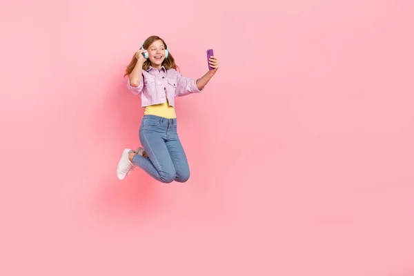 Foto de sueño lady jump hold phone search playlist use auriculares chaqueta jeans aislados color rosa fondo — Foto de Stock