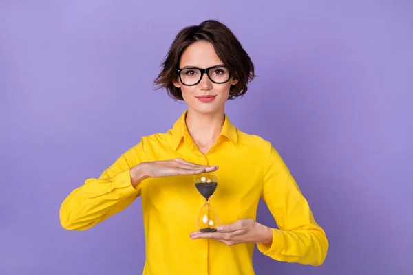 Foto di carino seo giovane signora tenere orologio indossare abiti gialli occhiali isolati su sfondo di colore viola — Foto Stock