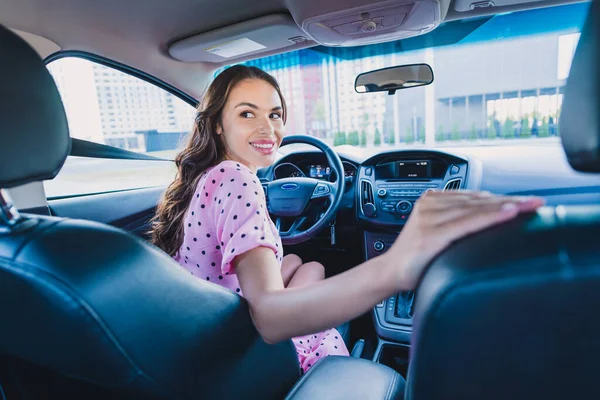 Fénykép a fiatal vidám csinos nő lovagolni auto parkolás közelében áruház nézd vissza mozgás vizsga vezetők engedély szabadban — Stock Fotó