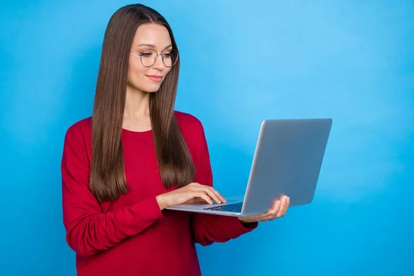 Foto di bella ragazza tipo laptop indossare occhiali camicia rossa isolato su sfondo di colore blu — Foto Stock