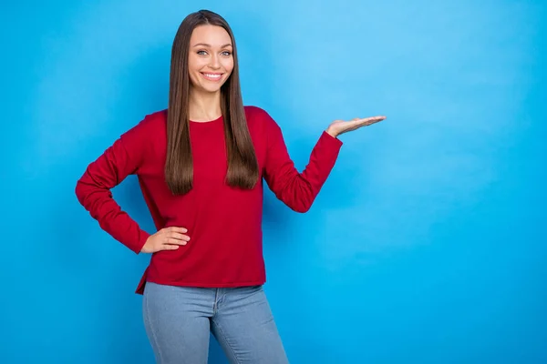 Foto van zoet lang kapsel dame houden lege ruimte dragen rood shirt geïsoleerd op blauwe kleur achtergrond — Stockfoto