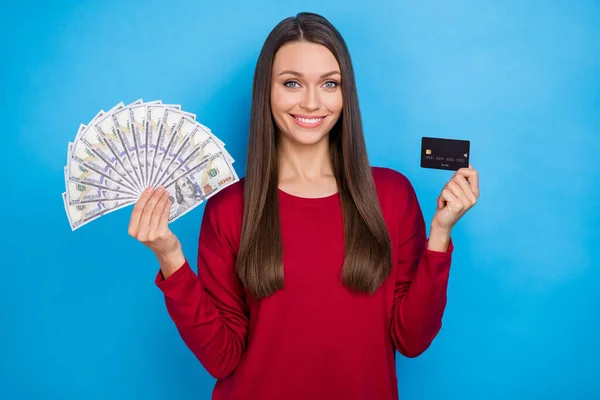 Fénykép a hűvös fiatal hölgy tartsa készpénz kártya viselése burgundi jumper elszigetelt kék színű háttér — Stock Fotó