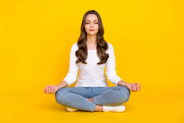 Foto de dulce mujer pacífica usar camisa blanca practicando yoga sentado piernas cruzadas aisladas color amarillo fondo —  Fotos de Stock