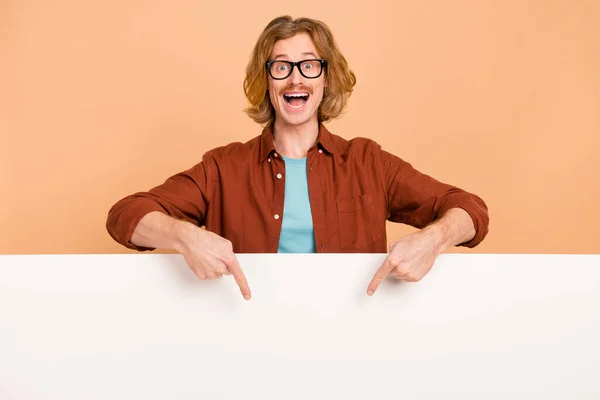 Porträtt av stilig trendig glädje förvånad rödhårig kille som visar nya annons kopia utrymme isolerad över beige pastell färg bakgrund — Stockfoto