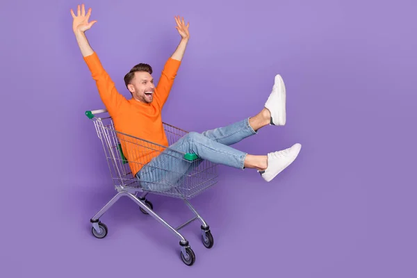Full length photo of cheerful overjoyed laughing man riding in trolley cart isolated on purple color background — ストック写真