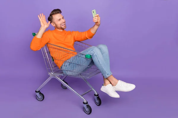 Photo of excited man sit in trolley have video conversation meeting with his girlfriend isolated on violet color background — ストック写真
