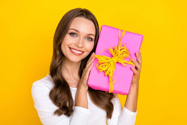 Foto de agradable positivo alegre linda dama mantenga presente caja táctil mejilla desgaste camisa blanca aislado color amarillo fondo —  Fotos de Stock