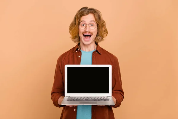 Portrait d'un beau gars aux cheveux roux gai tenant l'espace de copie d'ordinateur portable isolé sur fond beige couleur pastel — Photo