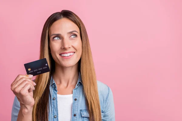 Foto av ung glad kvinna intresserad hålla bankkort ser tomt utrymme vinst lön isolerad över rosa färg bakgrund — Stockfoto