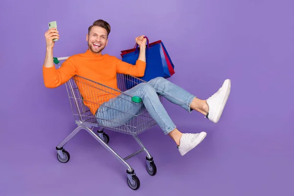 Full body photo of good mood excited man go shopping during black friday sale discount isolated on purple color background — ストック写真