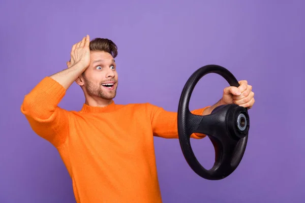 Foto de chico sorprendido impresionado desgaste suéter naranja conducción coche brazo cabeza buscando espacio vacío aislado color violeta fondo —  Fotos de Stock