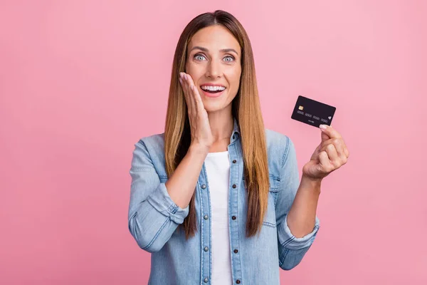 Fénykép a fiatal vidám nő kar touch arc wow hold hitelkártya profit fizetés elszigetelt felett rózsaszín színű háttér — Stock Fotó