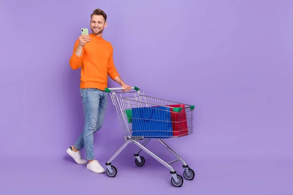 Full bild av positiva känslor man gå shopping chatta med vänner i telefon isolerad på violett färg bakgrund — Stockfoto