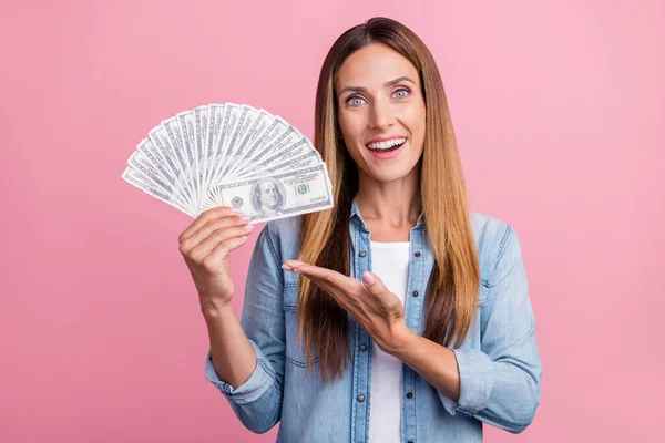 Foto av ung glad flicka visar inkomst vinst nytta kontanter dollar promo isolerad över rosa färg bakgrund — Stockfoto