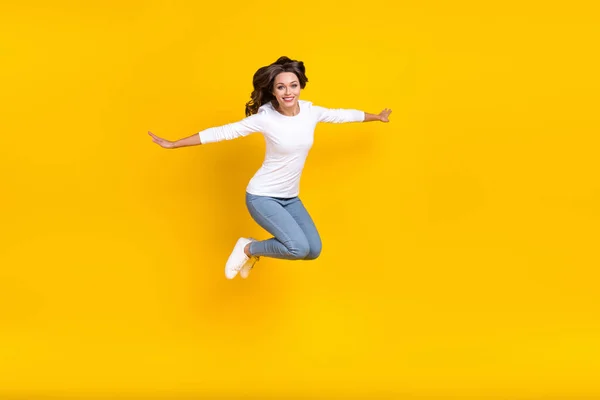 Foto van glanzende lieve vrouw dragen witte shirt springende armen zijden lopen geïsoleerde gele kleur achtergrond — Stockfoto