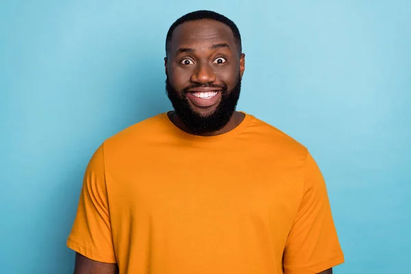 Фото довольно фанки парень носить оранжевую футболку улыбаясь показывая белые зубы изолированный синий цвет фона — стоковое фото