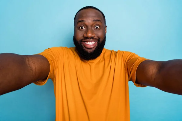Foto von lustigen fröhlichen Kerl tragen orangefarbene T-Shirt Aufnahme Selbstvideo lächeln isoliert blaue Farbe Hintergrund — Stockfoto