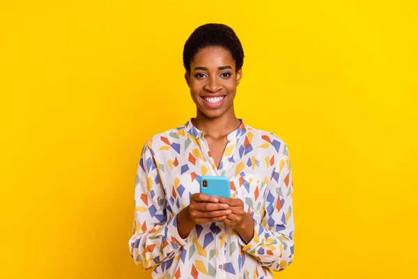 Fotografie veselý blogger osoba držet telefon zubatý úsměv vzhled fotoaparát izolované na žlutém pozadí — Stock fotografie