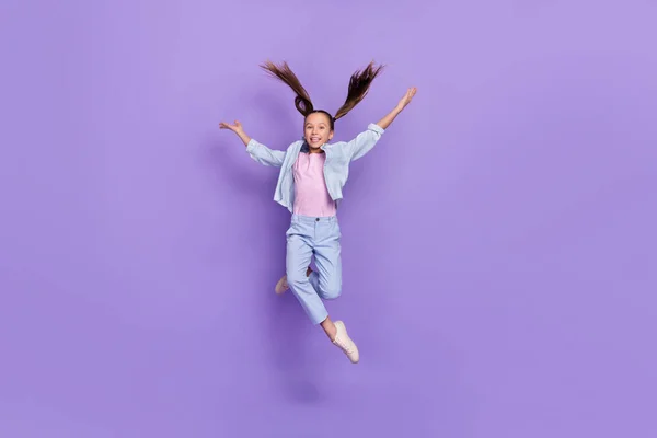 Foto von niedlichen entzückenden kleinen Schulmädchen gekleidet Jeans-Shirt springen hoch fallen isoliert violette Farbe Hintergrund — Stockfoto