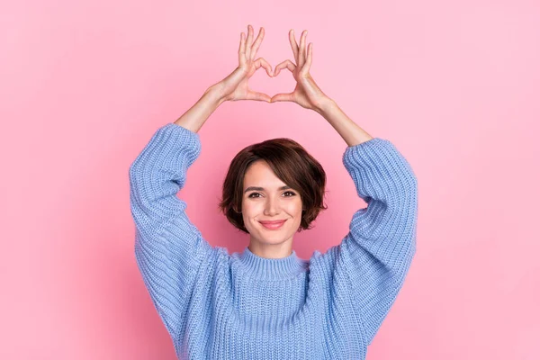 Retrato de magníficos brazos de dama positiva hacen símbolo del corazón por encima de la cabeza aislado en el fondo de color rosa —  Fotos de Stock