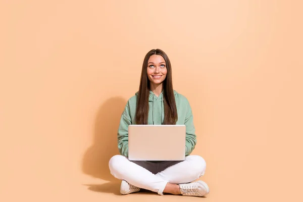Portret atrakcyjnej, wesołej, ciekawej dziewczyny siedzącej na laptopie, szukającej przestrzeni do kopiowania na beżowym pastelowym tle — Zdjęcie stockowe