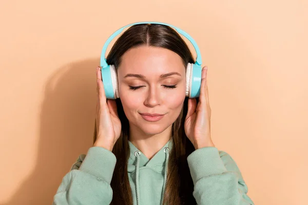 Porträt von attraktiven heiteren braunhaarigen Mädchen hören Hit einzigen Stereo isoliert über beige Pastellfarbe Hintergrund — Stockfoto