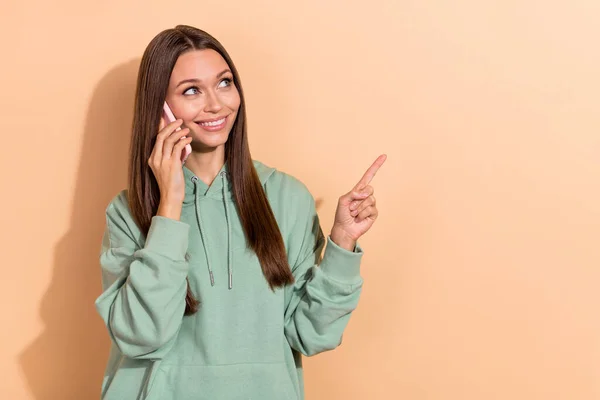 Portrait of beautiful trendy cheerful girl talking on phone showing copy space isolated over beige pastel color background — ストック写真