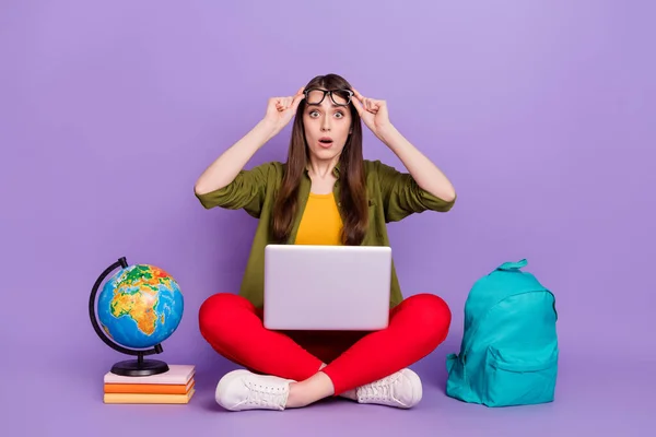 Retrato de chica atónita atractiva usando el ordenador portátil haciendo tarea de ciencias tarea aislado sobre violeta color púrpura fondo —  Fotos de Stock
