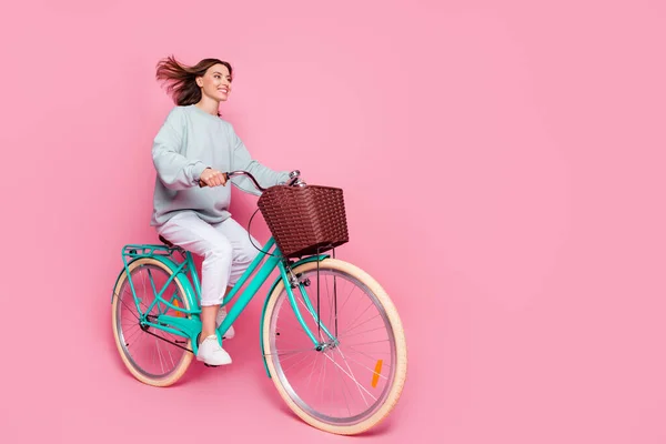 Full body profil boczny zdjęcie młodej dziewczyny wyglądają puste miejsce cieszyć rower jazdy odizolowany na różowy kolor tła — Zdjęcie stockowe