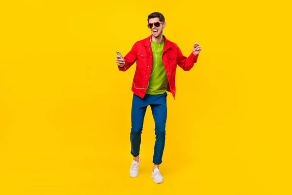 Pełne ciało zdjęcie funky młody facet taniec słuchać muzyki nosić okulary spodnie trampki izolowane na żółtym tle — Zdjęcie stockowe